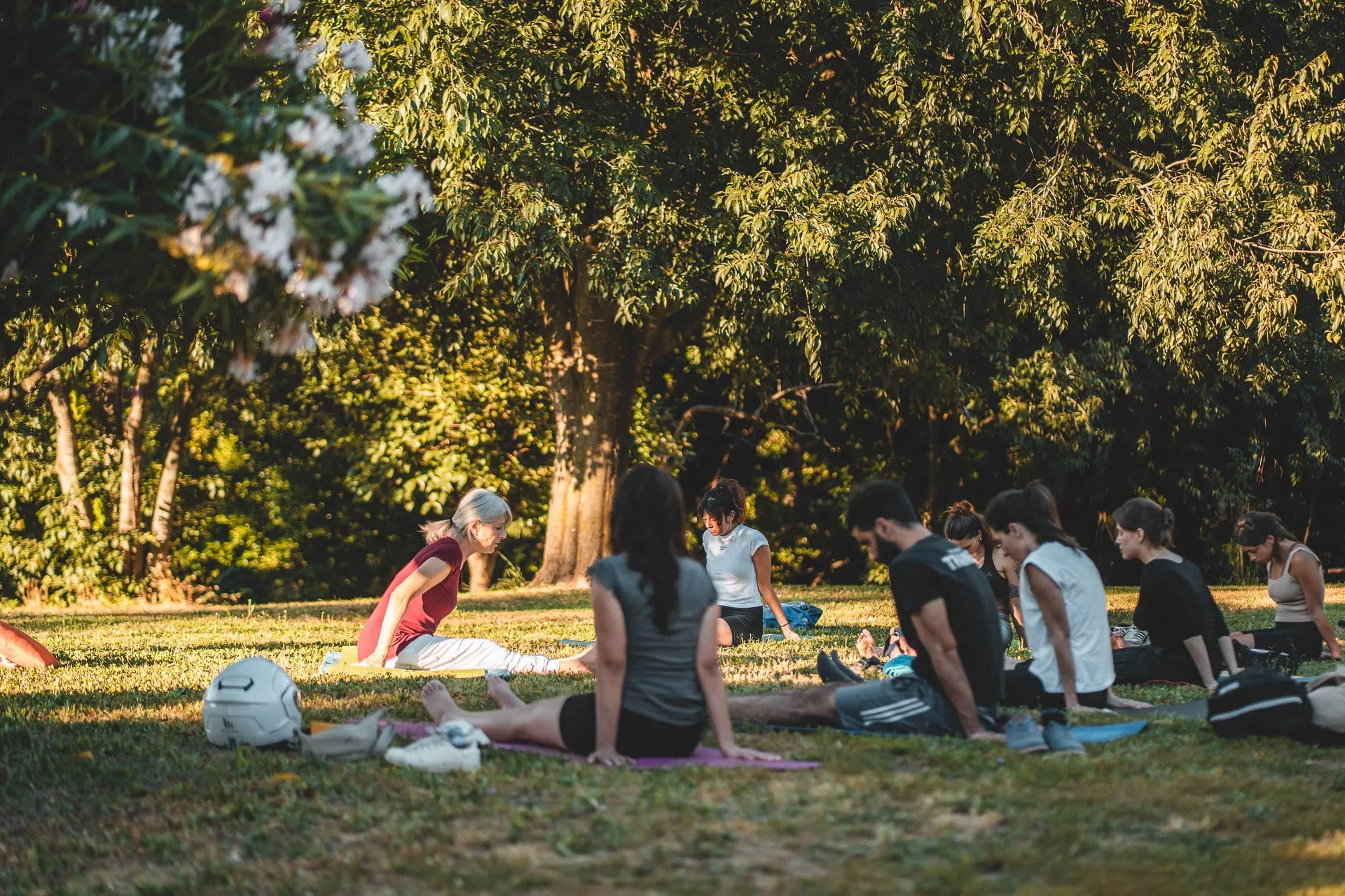 Persone sui tappetini sul prato durante una lezione all'aperto