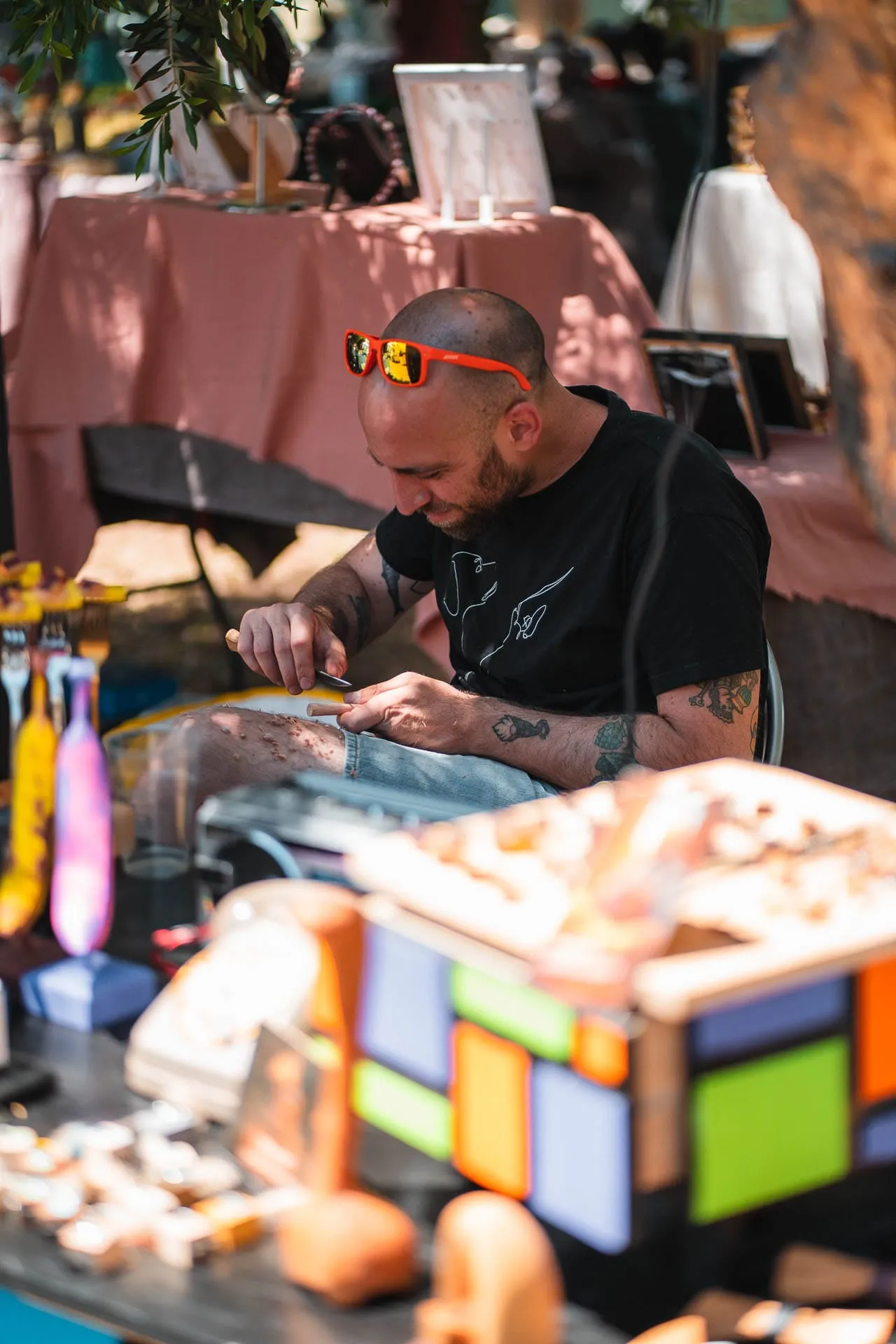 An artisan at work at his stall, among colourful objects