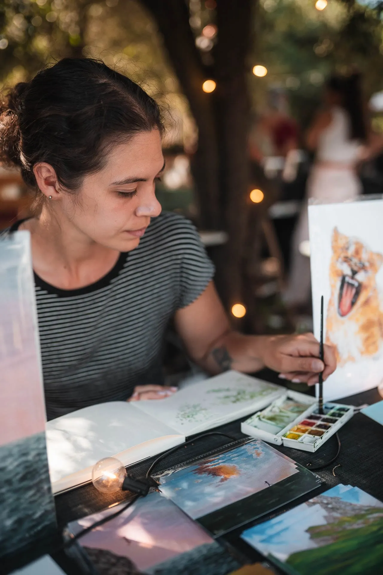 An illustrator painting in watercolour at her stall