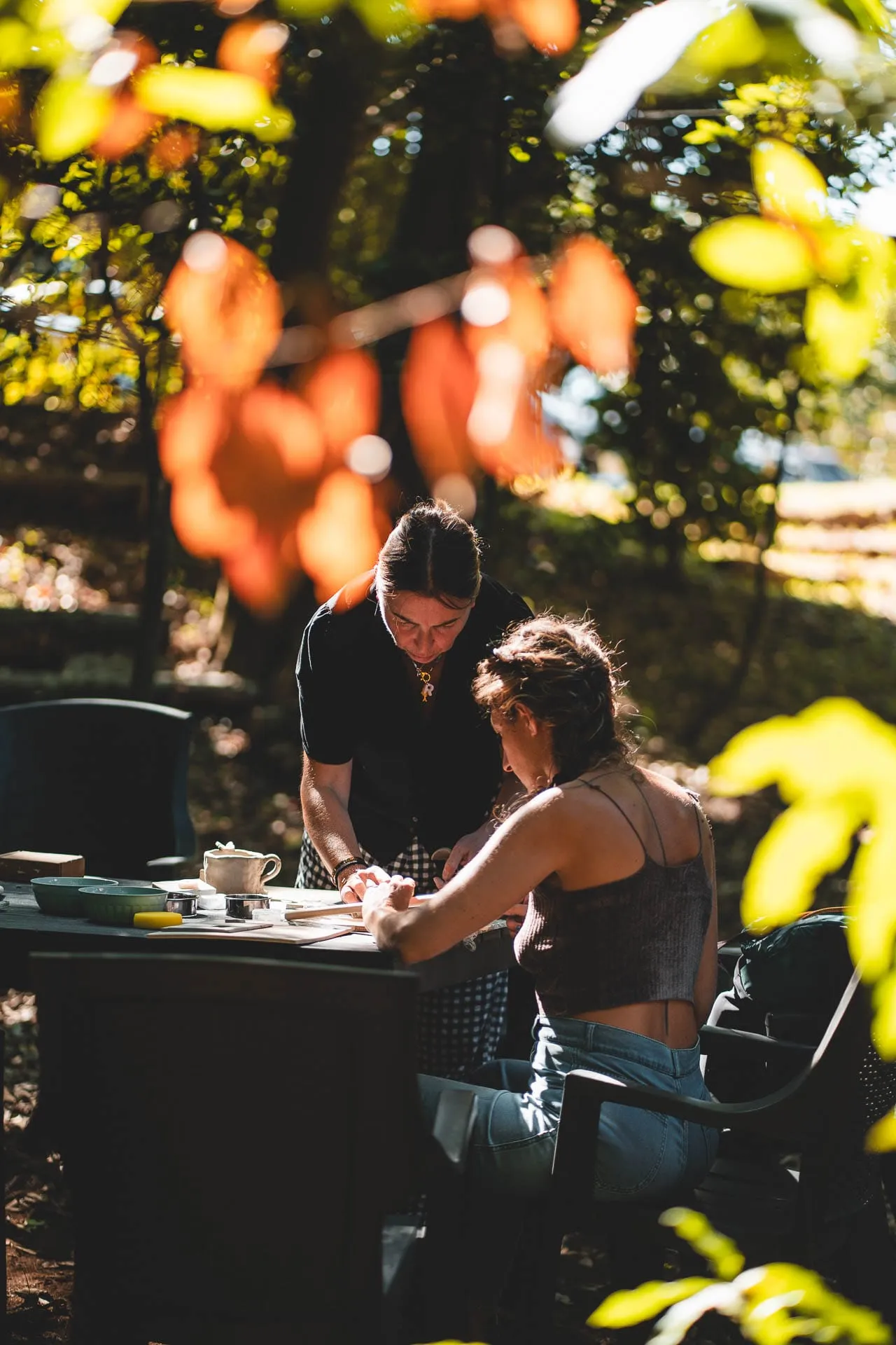 Due persone al lavoro a un tavolo del workshop, tra le foglie d'autunno